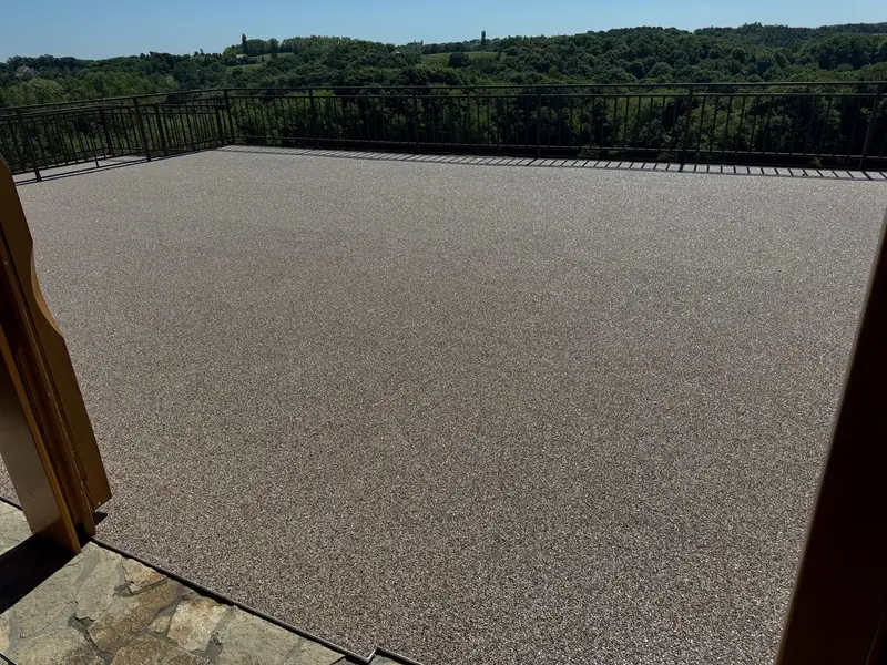 Grosse Dachterrasse mit beiger Körnung und Blick über die Hügel