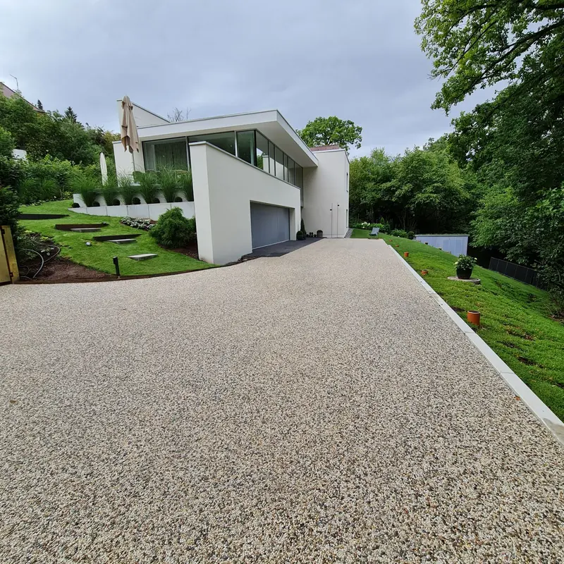 Zufahrt mit sandfarbenem Steinteppich zu einer Garage