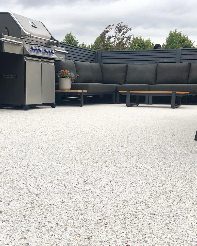 Terrasse mit cremefarbenem Steinteppich und Loungemöbeln
